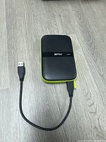 Full view of Silicon Power Armor A60 drive with attached USB cable on wood surface