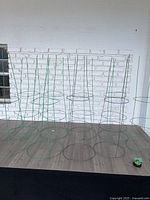 Front view of all nine green metal plant support rings standing upright on floor