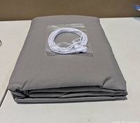 Folded grey grounding sheet with cord packet on top