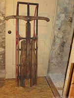 Full view of antique sled leaned against wall