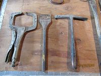 Locking welding clamp, toothed chisel, T-head hammer on work surface