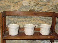 Three white ceramic planter pots on shelf