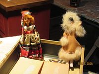 Both dolls standing inside decorative butterfly box