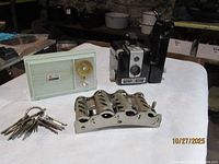 Group shot showing all four items: Brownie Hawkeye camera with flash bracket, Philco radio, coin dispenser, keyring with keys