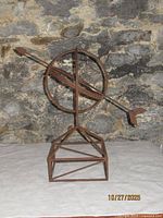 Front view of wrought iron armillary-style sculpture showing arrow and base