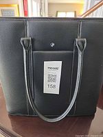 Front view of BMW black leather tote bag showing badge, exterior pocket and handles