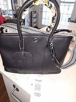Front view of black leather tote with crossbody strap attached