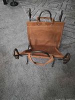 Front view of iron log rack with leather sling attached