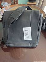 Front of black leather Levenger tote bag showing flap and shoulder strap