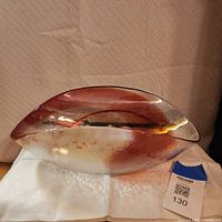 Side view showing elongated oval Murano glass bowl with red swirl