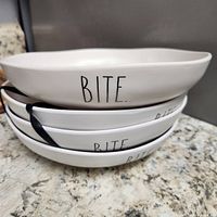 Stack of four white bowls showing "BITE." text
