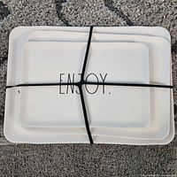 Stacked platters secured with elastic, top platter shows ENJOY. text