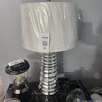 Full view of first chrome lamp with shade wrapped in plastic