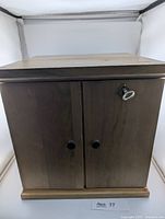 Front view of closed two-door wooden coin cabinet with key in lock