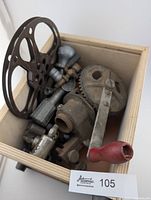 Overview of wooden box showing film reel, crank gear assembly and mixed metal parts
