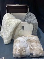 All three blankets draped over and inside cream fabric bin