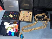 Overview of three Joan Rivers boxes showing interchangeable stone tray, bee brooch set, necklace with chain and stones