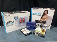 Full lot showing boxed Homedics massagers, Tommie Copper TENS device, and two Viridian electrode pad packs