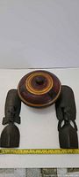 Pair of African busts displayed beside lidded bowl with measuring tape for scale