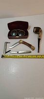Group shot showing all pocket cutters, Longchamp pipe, sunglasses and case with measuring tape for scale
