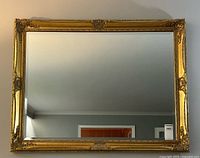Full view of rectangular gilt mirror on wall