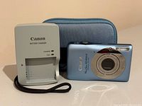 Front view of Canon PowerShot SD1300 IS camera, Canon battery charger and zippered case
