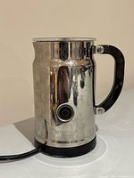 Front view showing stainless steel body, handle, button and cord