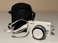 Camera with lens cap attached, neck strap, and carry case