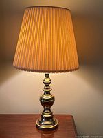 Full view of brass table lamp with shade illuminated