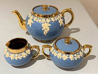 Full view of teapot, covered sugar bowl and creamer showing colour, pattern and condition