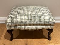 Front view of rectangular plaid ottoman with cabriole legs