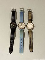 Three wristwatches laid side by side showing fronts and straps
