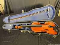 Violin inside open hard shell case with bow