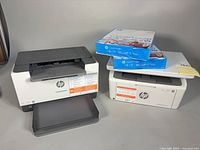 Both printers side by side with two reams of paper