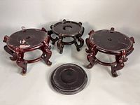 Three legged wooden stands and one flat base displayed together