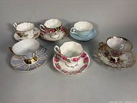 Group of six teacup and saucer sets displayed