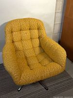 Front three-quarter view of mustard yellow swivel lounge chair showing tufted upholstery and overall design