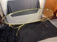 Full view of oval gilt metal coffee table with glass top