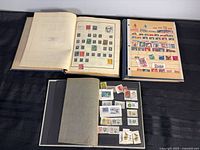 Overview of three open albums showing assorted stamps