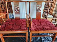 Front view of both rosewood chairs showing dragon carvings and red cushions