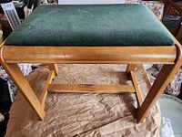 Full view of stool showing wood frame and green cushion