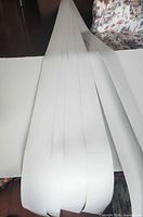 Stack of white PVC blind slats showing width