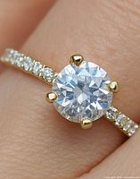 Top view of ring on finger showing round centre stone and accent diamonds on band