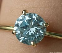 Close-up of round blue diamond solitaire on yellow gold band