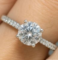 Close-up of ring on finger showing centre stone and pavé band