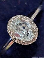 Front view of silver ring showing oval aquamarine-colored CZ center with surrounding clear CZ halo