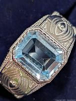 Front view showing emerald-cut blue topaz set in detailed silver mount