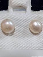 Close-up of both pearl stud earrings showing size, luster and silver posts