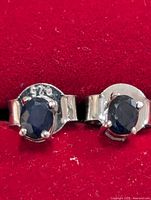 Close-up of both sterling silver sapphire stud earrings showing 925 stamp and gemstone detail