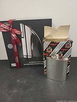 Front view of boxed Trudeau automatic lever corkscrew alongside Sheffield Mint flask and its box